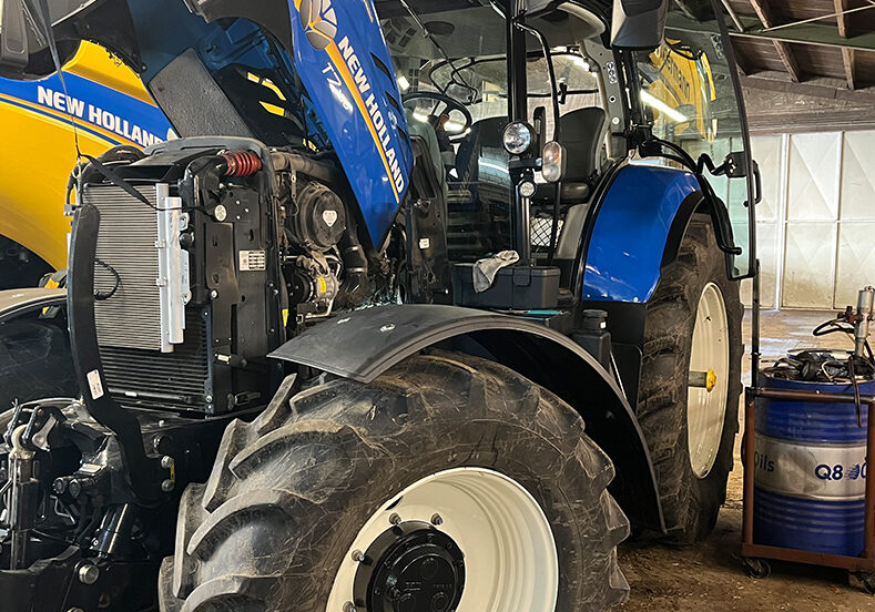 New-Holland-Traktor bei der Wartung in der eigenen Werkstatthalle